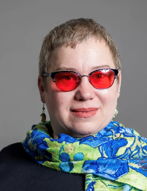 photo of a white woman with short light hair and red lensed glasses